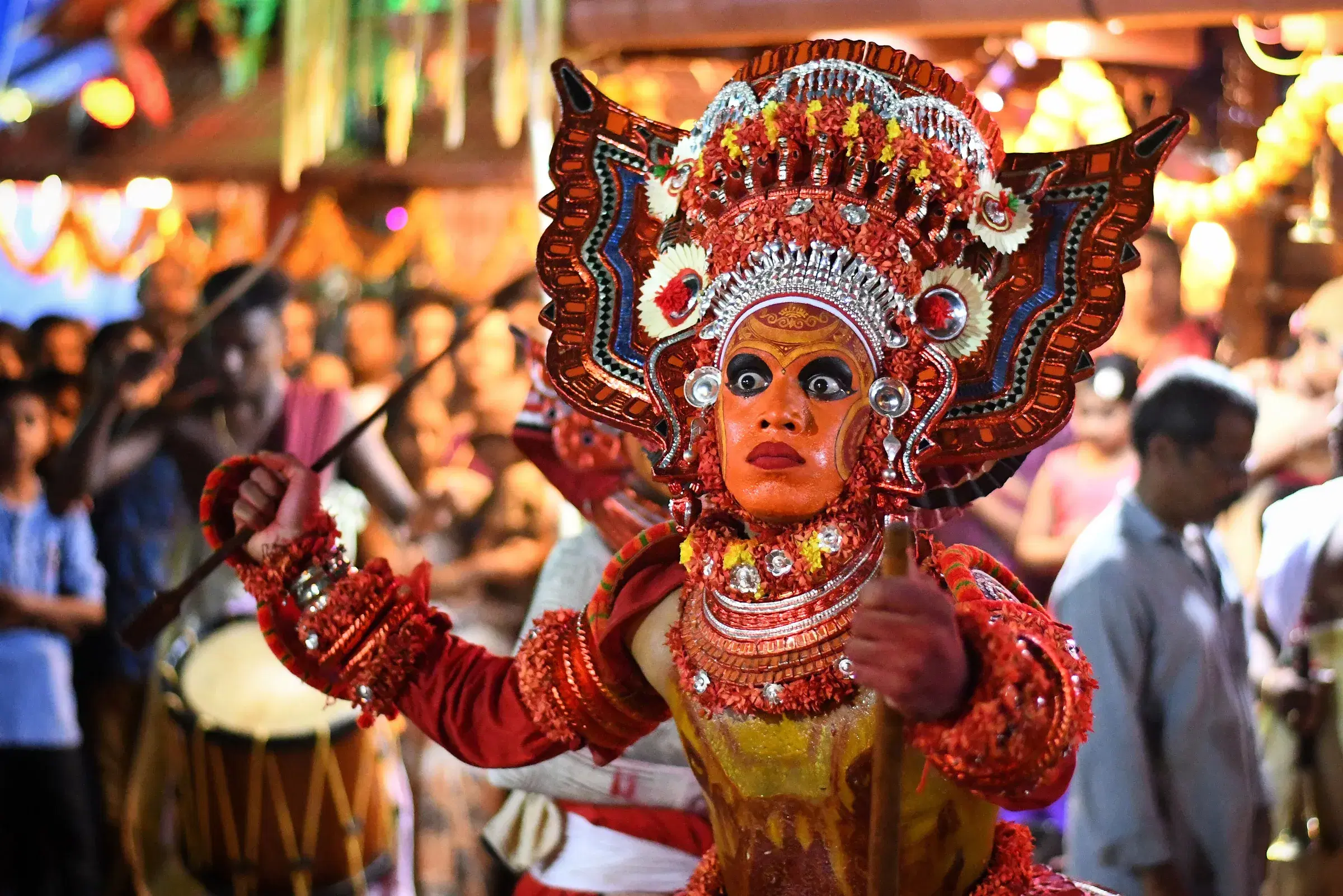 A Theyyam performer in a red headdress